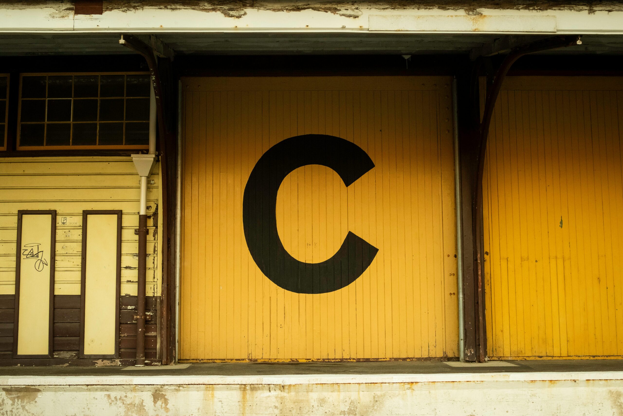 Yellow warehouse door marked with large 'C', vintage style in Fremantle.